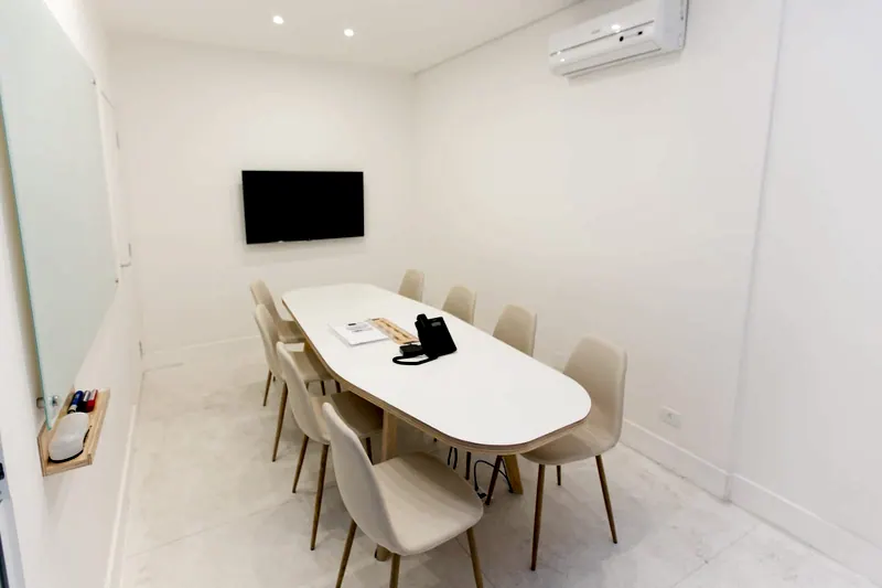 Sala de reunião branca com mesa oval e cadeiras claras